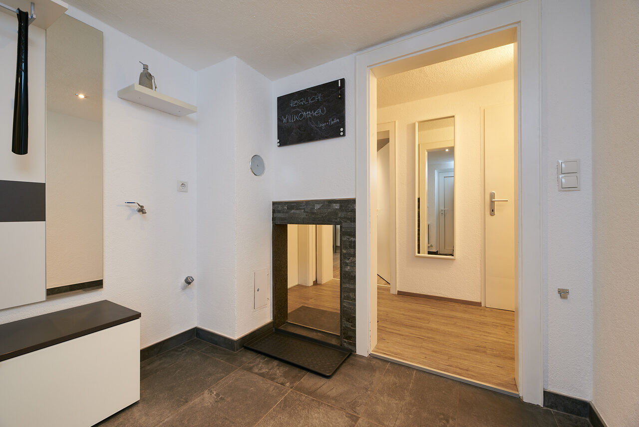 Eingangsbereich der Ferienwohnung mit Garderobe, Tafel mit Willkommensgruß und Blick in den Gang.